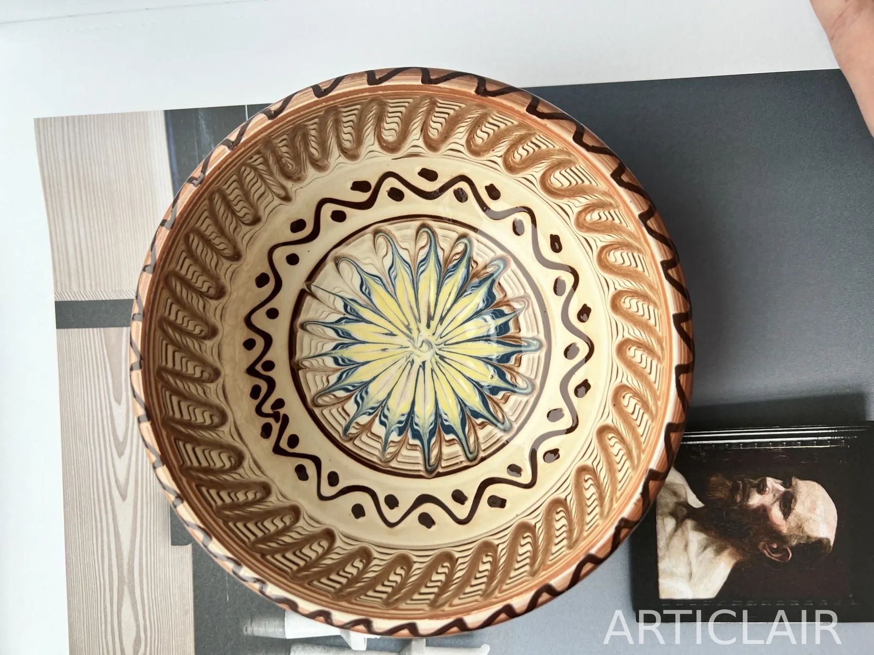 A decorated ceramic plate with a yellow-and-blue sun motif at the center