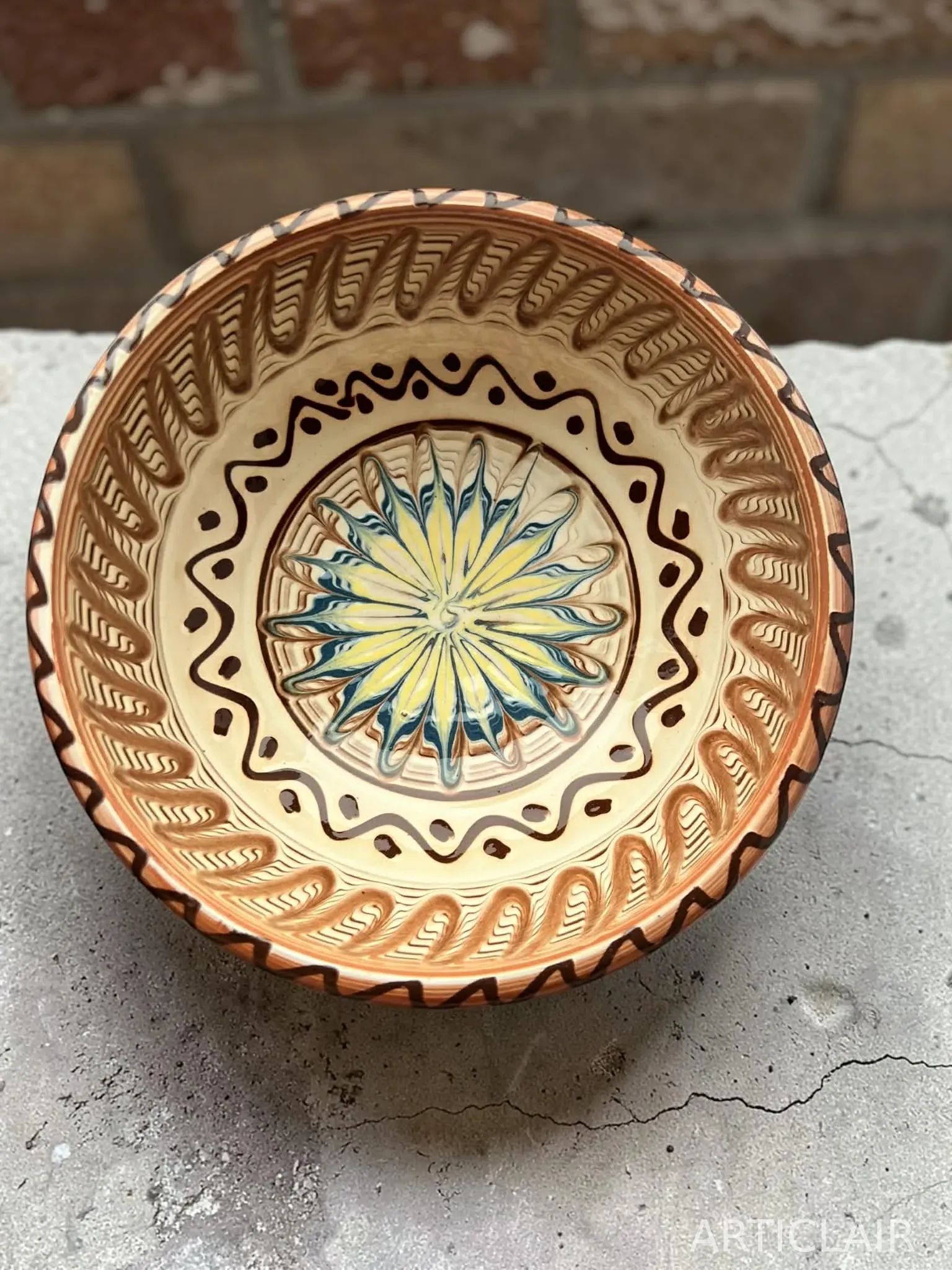 A decorated ceramic bowl with a yellow-and-blue sun motif at the center