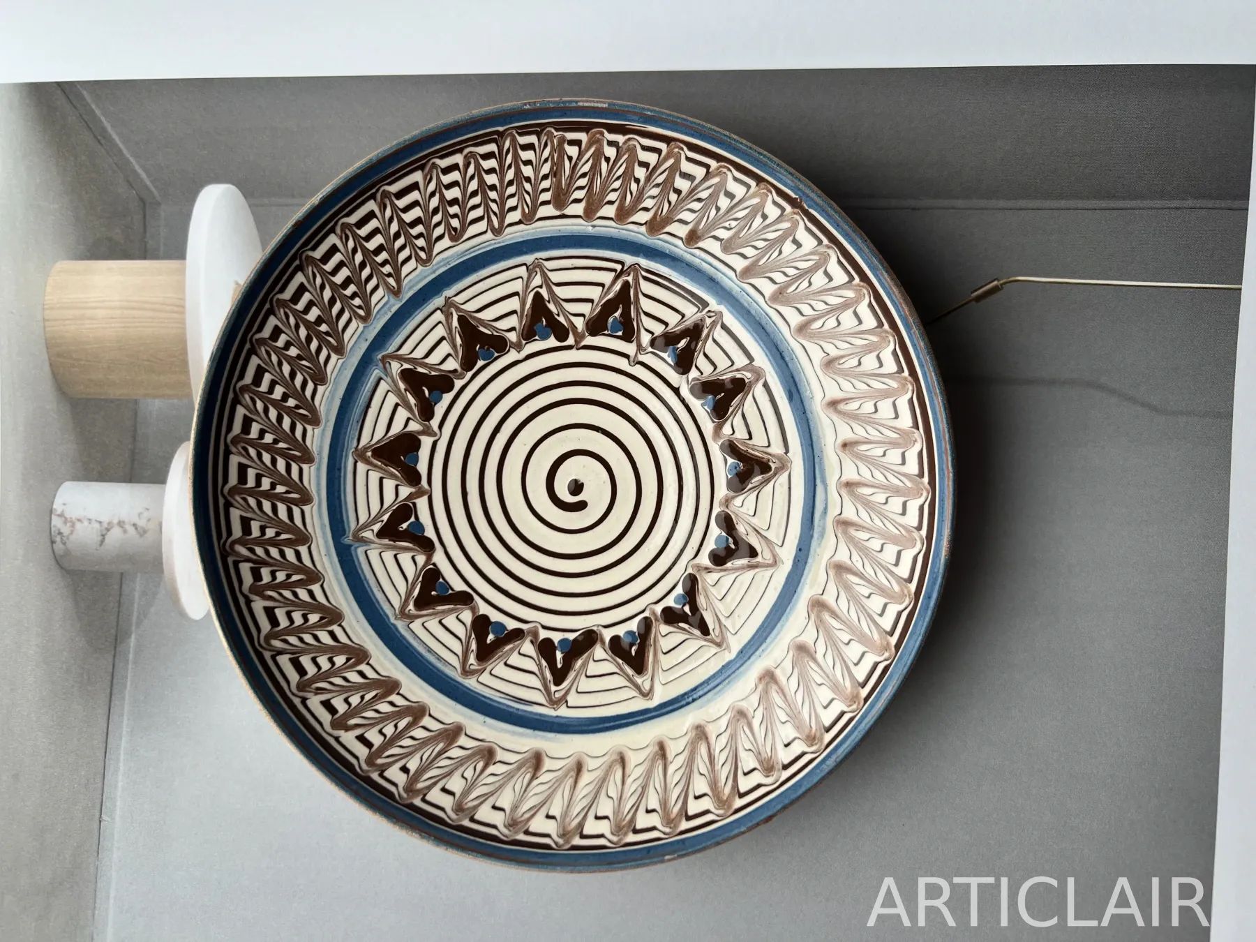 A ceramic plate with a spiral center, blue rim, and zigzag border