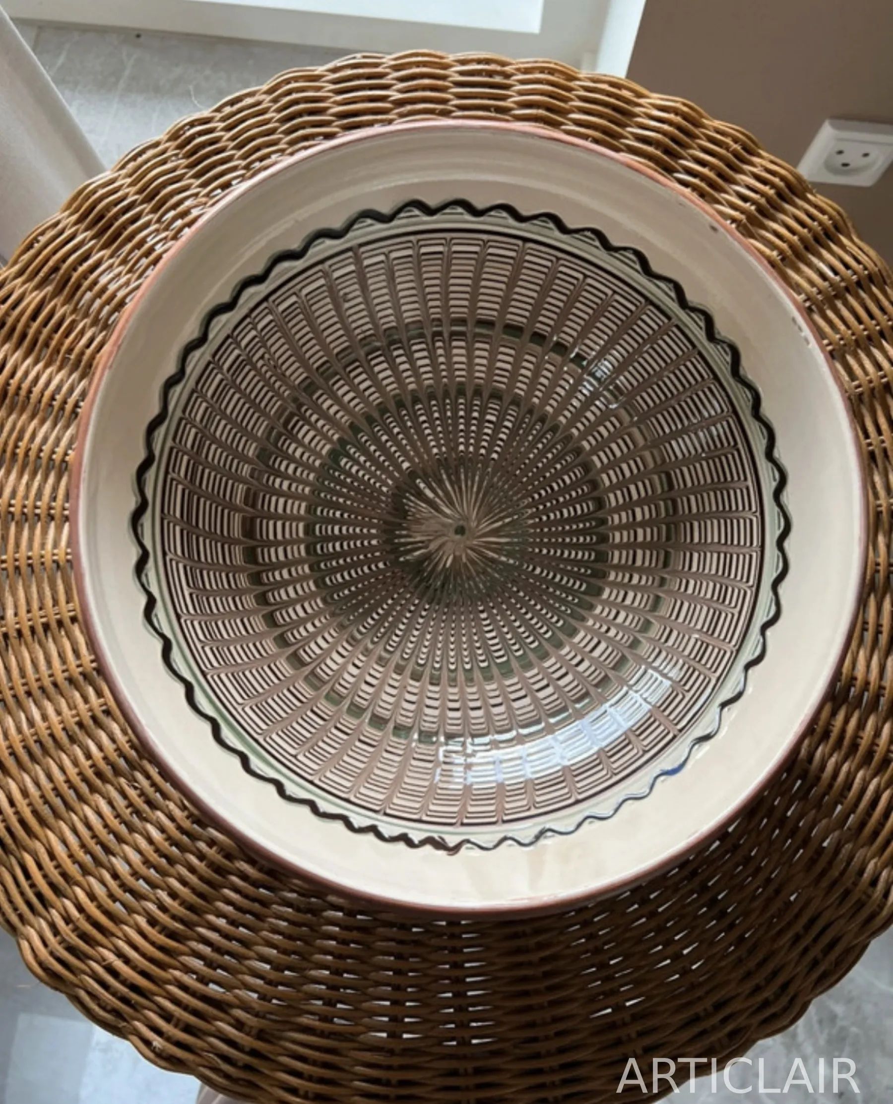 A ceramic bowl with dark linear decoration and a restrained central rosette