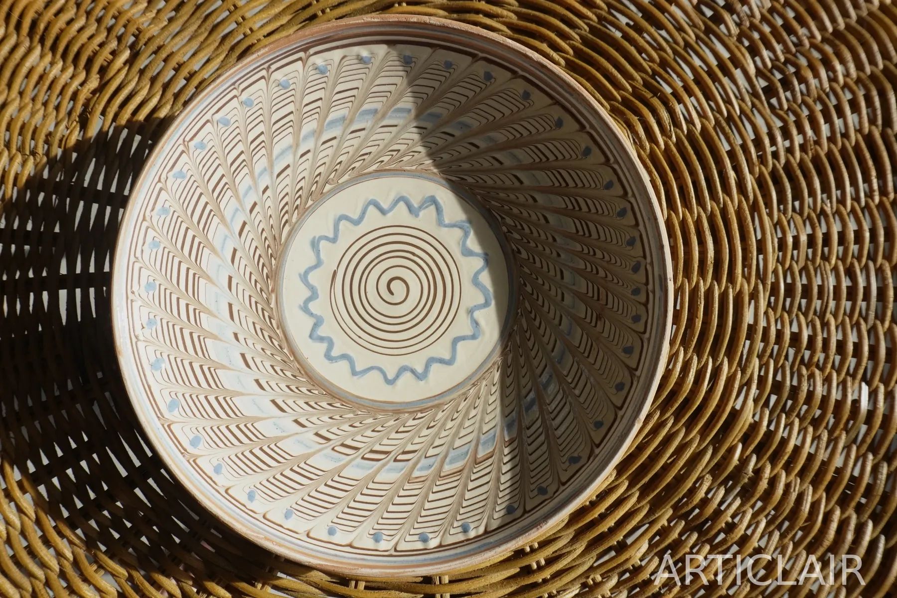 A ceramic plate with a drawn spiral center and pale blue rim accents