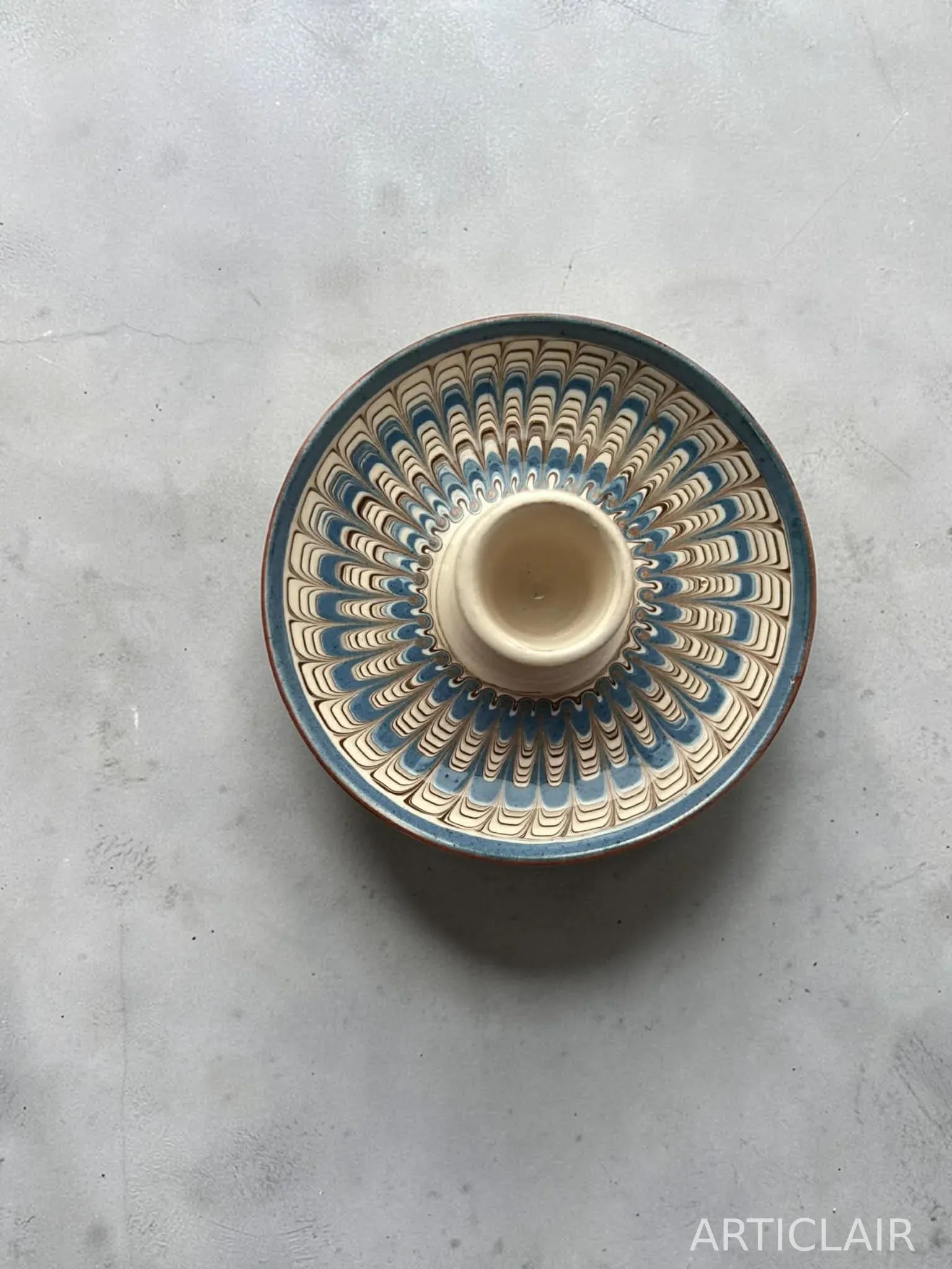 A large Horezu serving bowl with blue feathered decoration in a dark interior setting