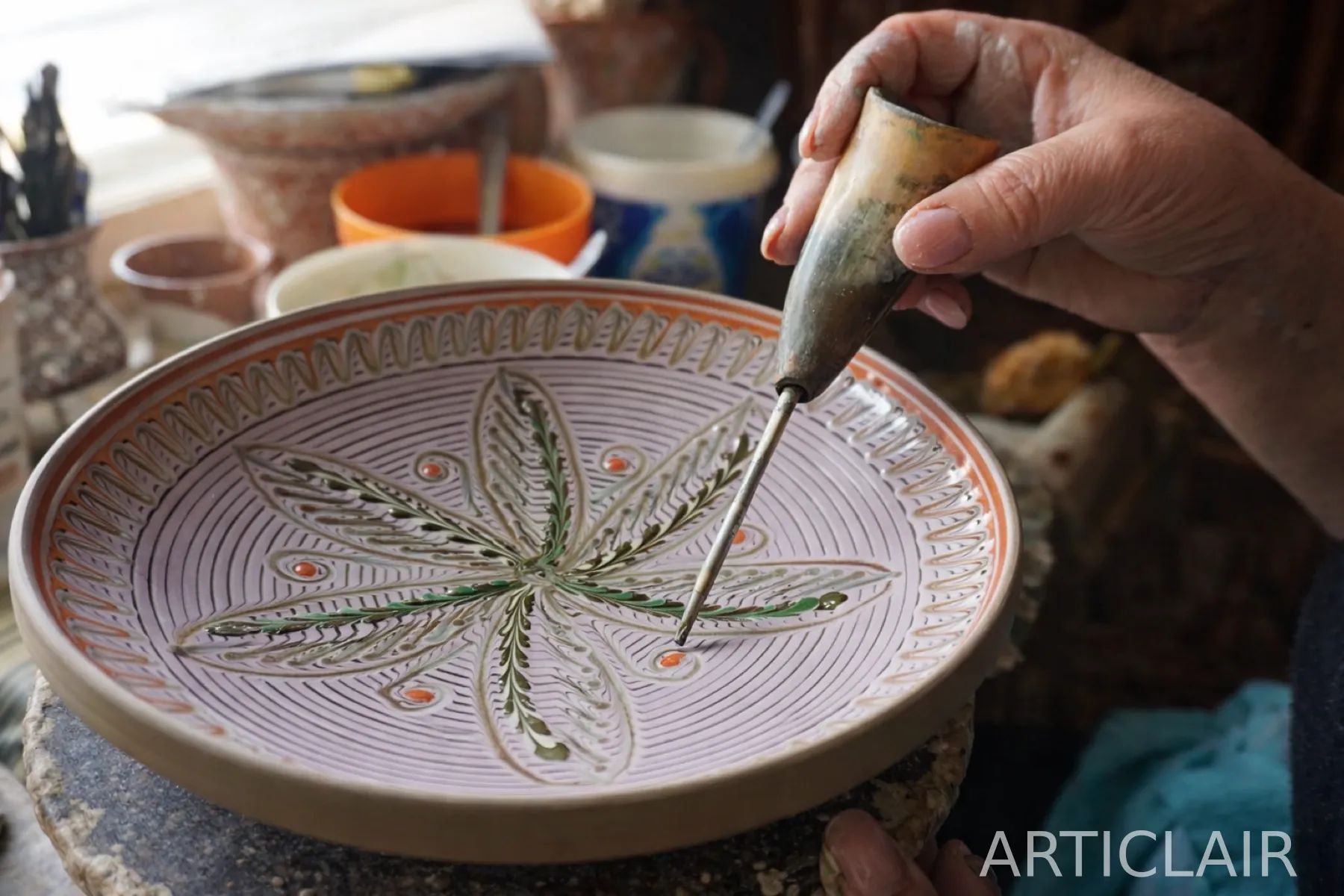 A close detail of a ceramic plate being painted by hand
